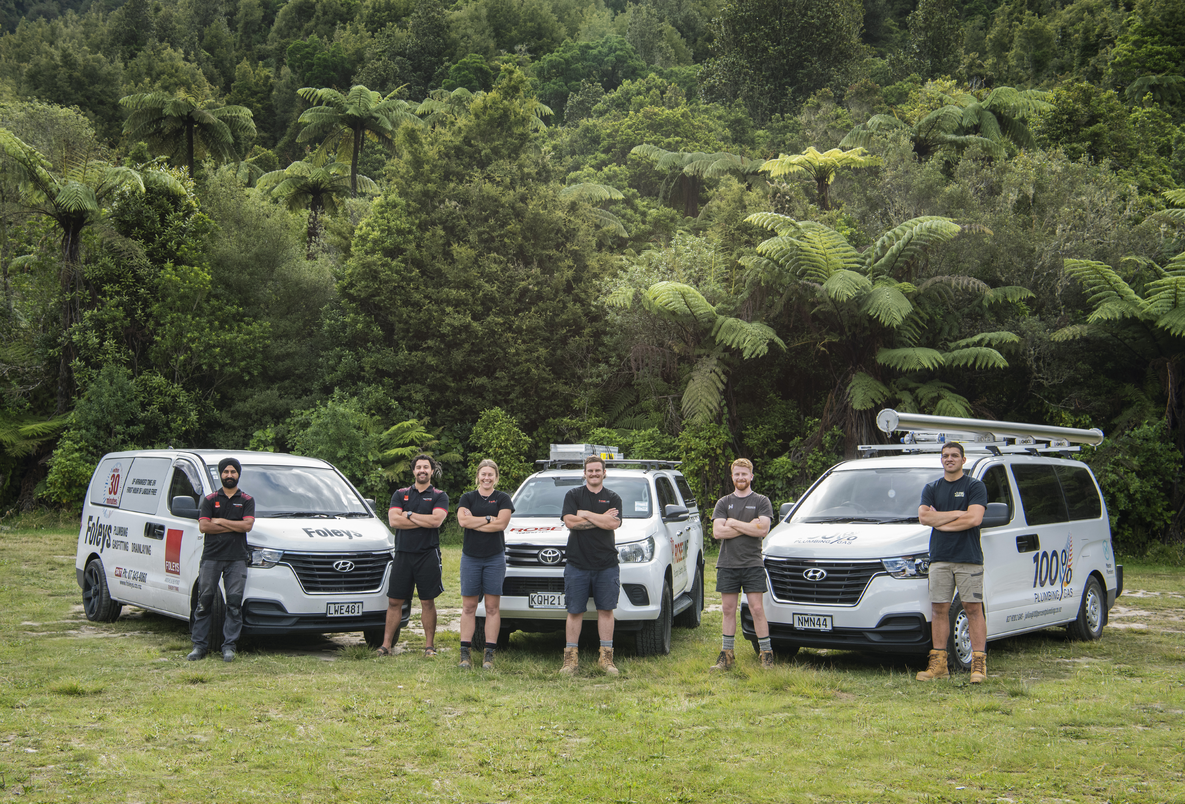 group of Master Plumbers standing proudly in front of their work vans